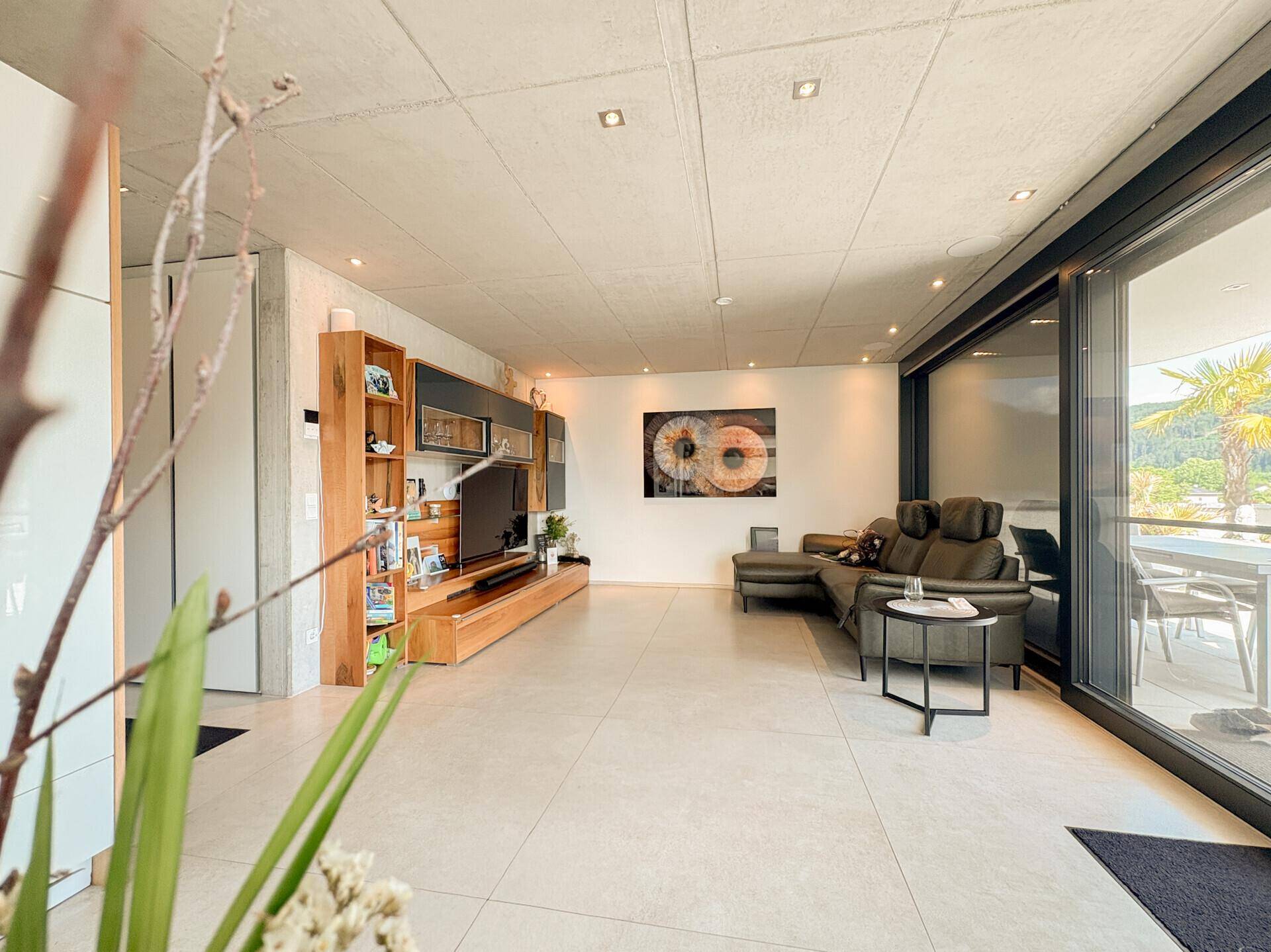 Geräumiges Wohnzimmer mit bequemer Couch, Medienmöbeln und Zugang zur Terrasse.