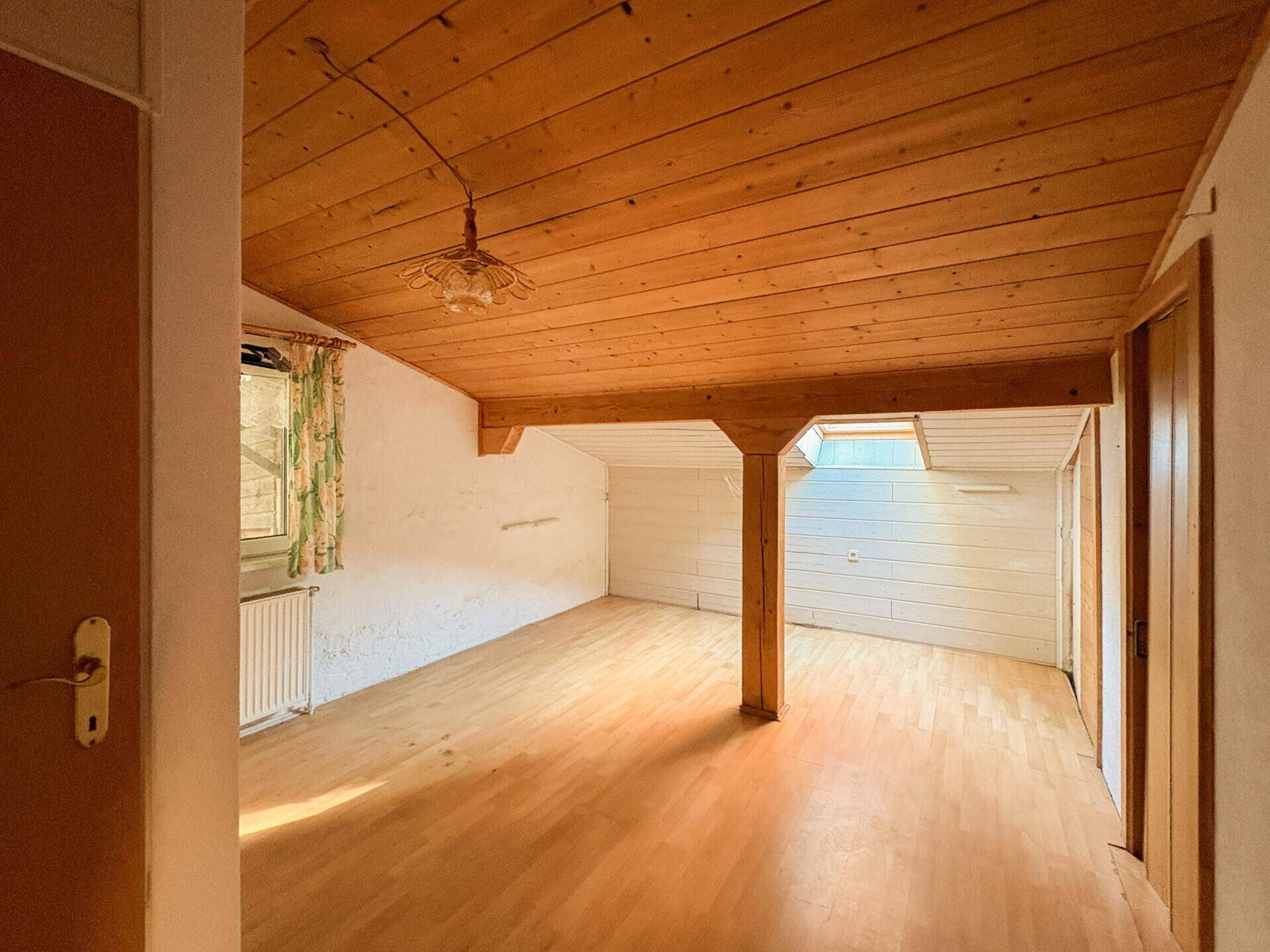 Helles Schlafzimmer mit Holzfußboden, Holzdecke und einem Holzbalken.