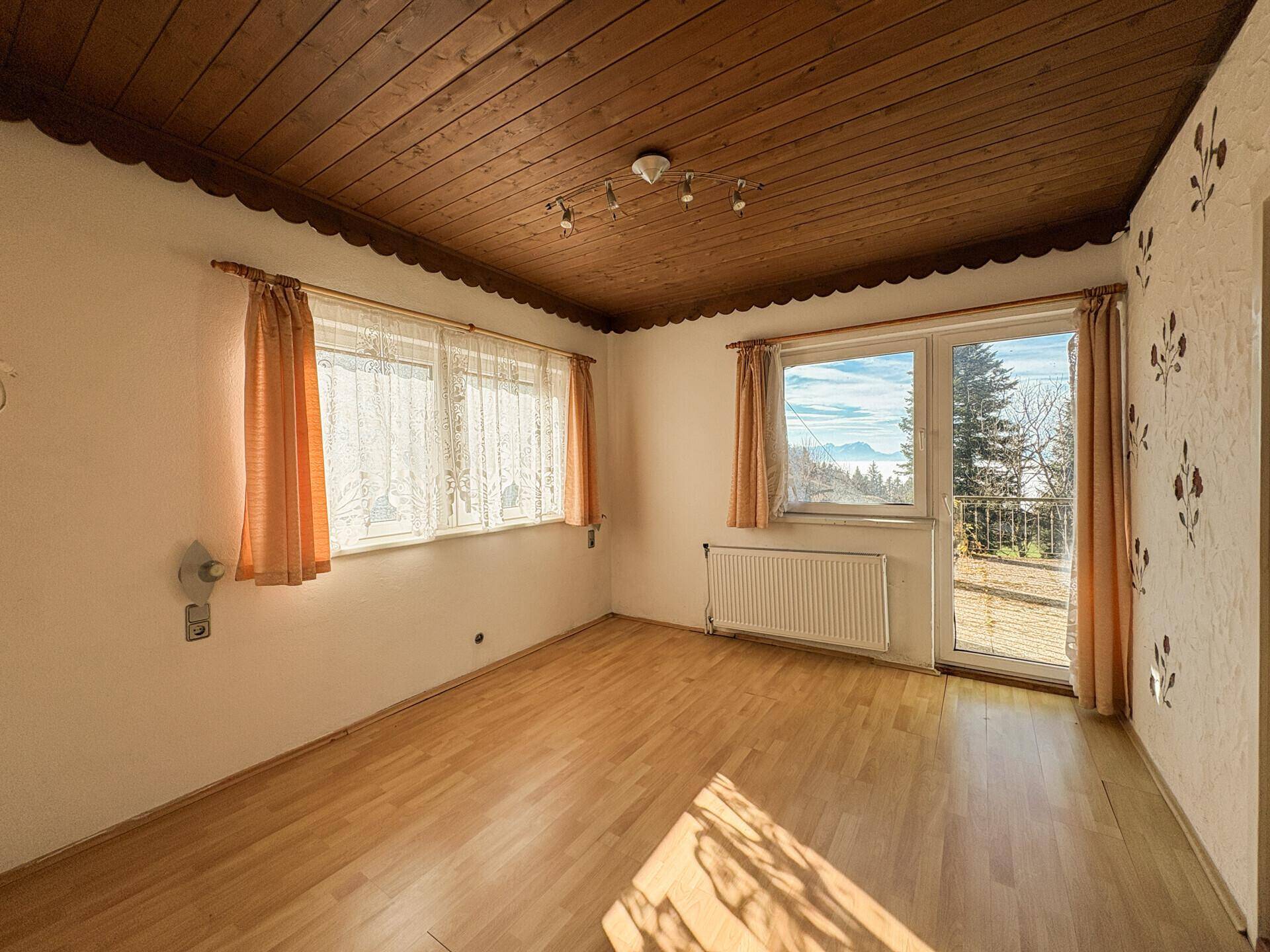 Schlafzimmer mit Holzfußboden, Holzdecke und Zugang zu einem Balkon mit Bergblick.