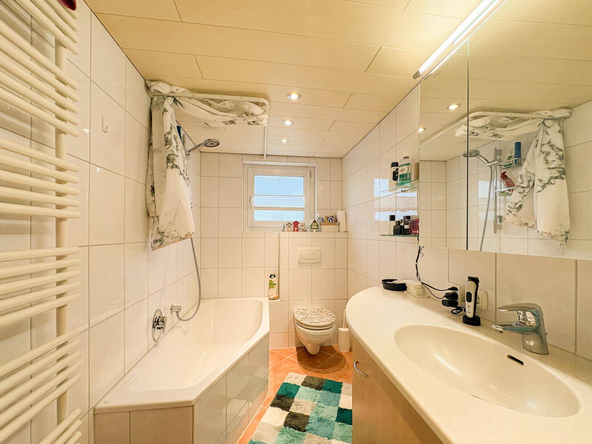 Badezimmer mit Badewanne, Dusche, Waschbecken und beheiztem Handtuchhalter.