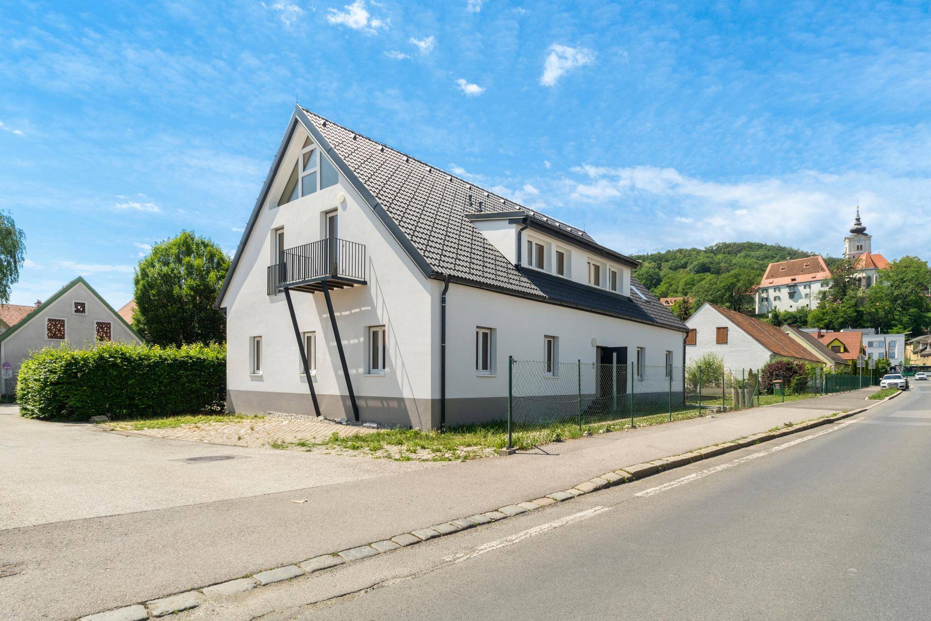 Ansicht des modernen Hauses von der Straße, mit klaren Linien und einem Balkon.