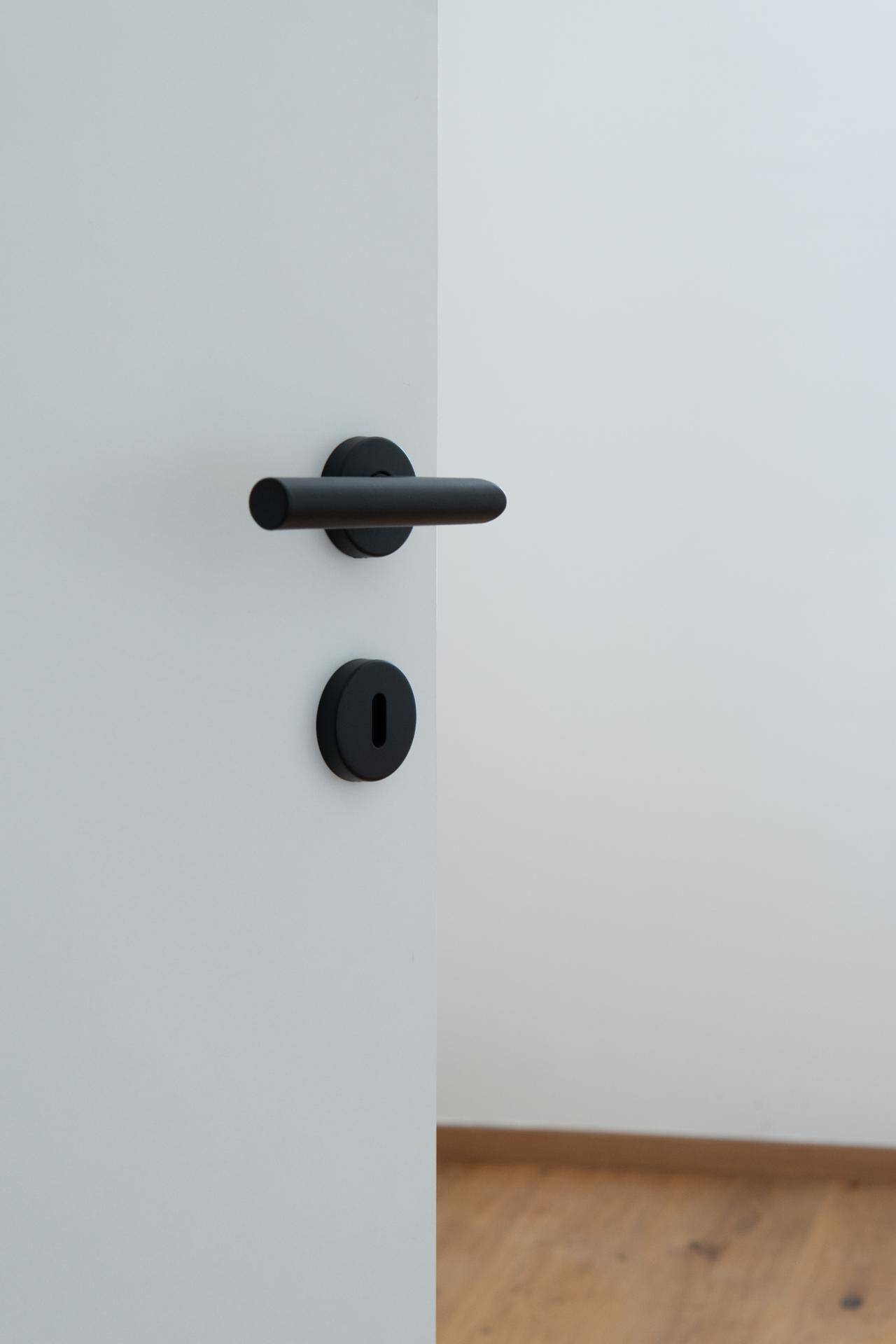 Moderne schwarze Türgriffe an einer weißen Innentür, minimalistisches Design.