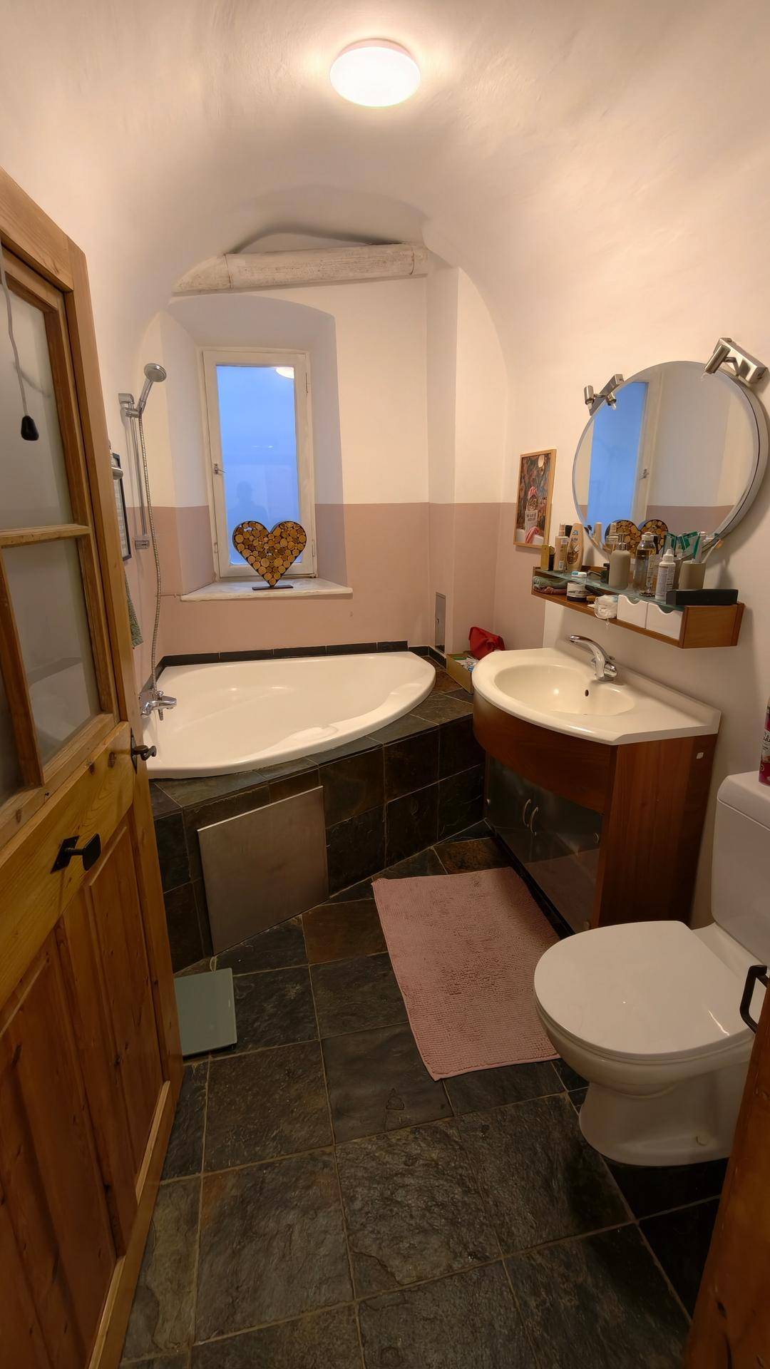 Badezimmer mit Badewanne, Waschbecken, Toilette und einem Fenster mit natürlichem Licht.