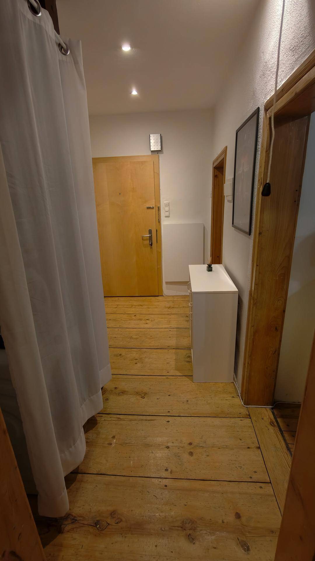Langer Flur mit Holzboden und mehreren Holztüren, die zu anderen Räumen führen.