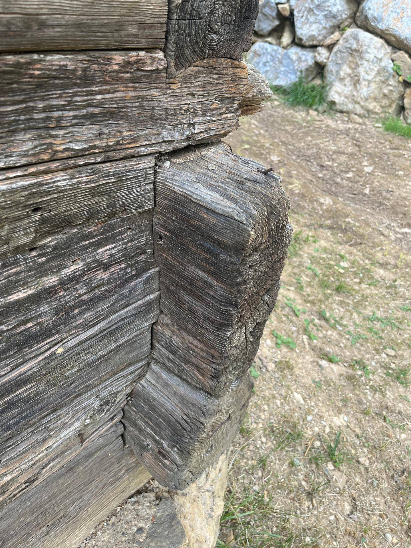 Nahaufnahme einer Hausecke mit verwittertem Holz und traditioneller Blockbauweise.