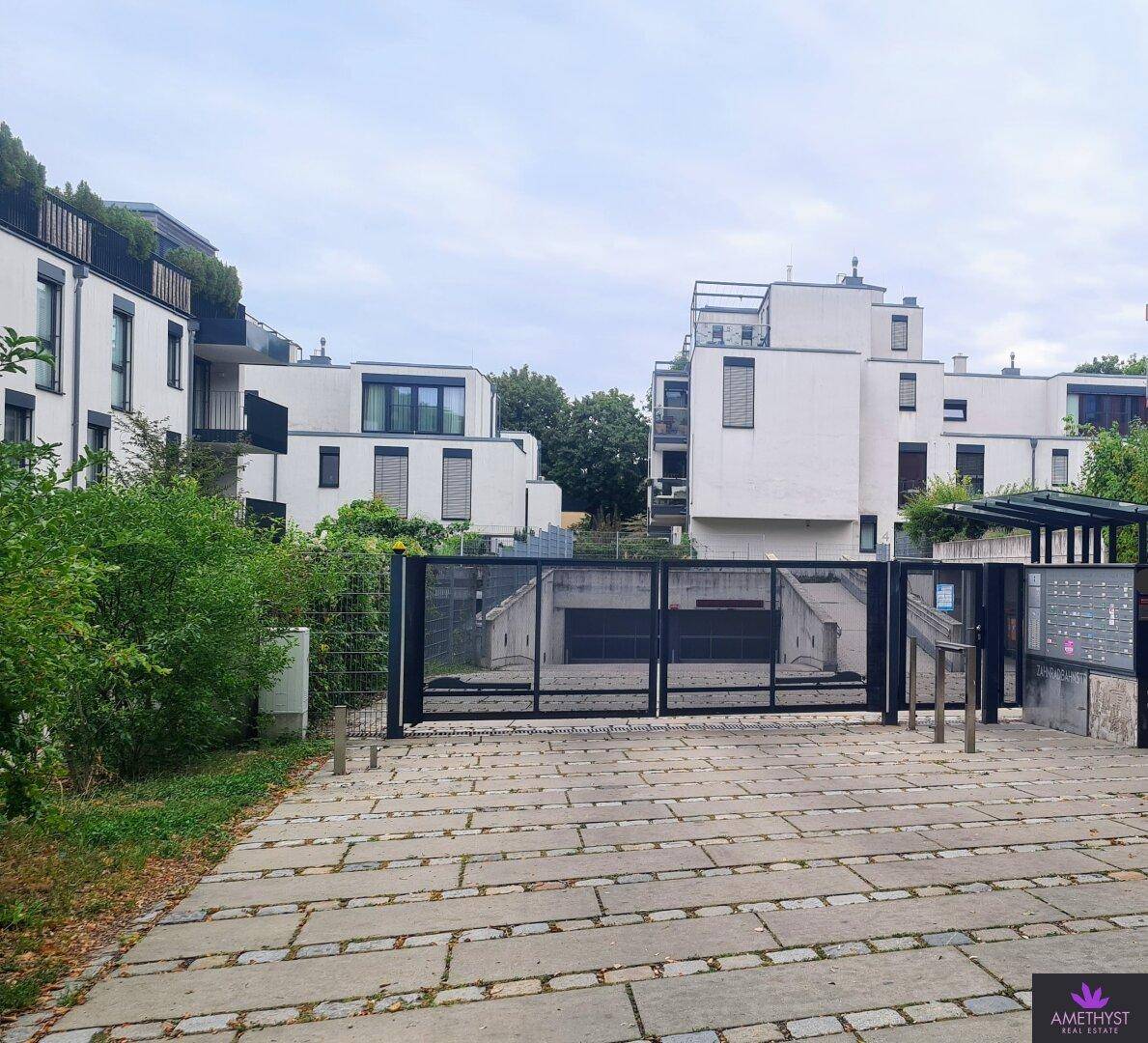 Moderne Wohnanlage mit Tiefgaragenzufahrt und grüner Umgebung.