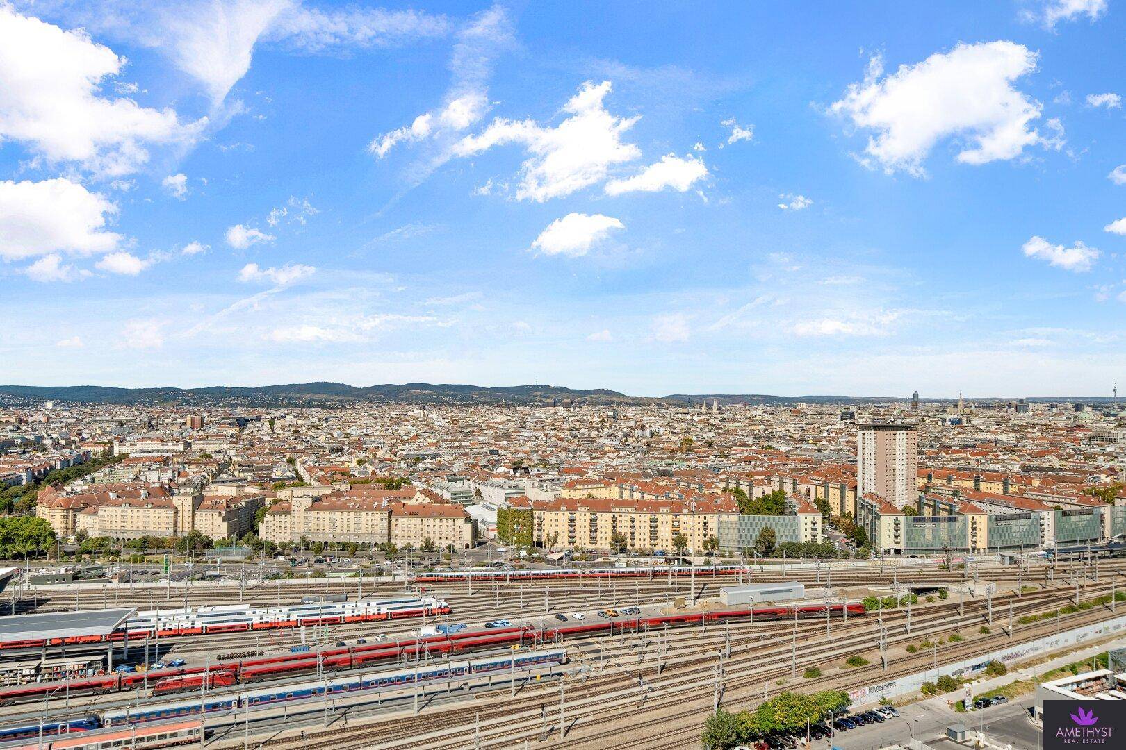 Panoramablick über die Stadt mit Bahnanlagen und Wohngebäuden unter blauem Himmel.