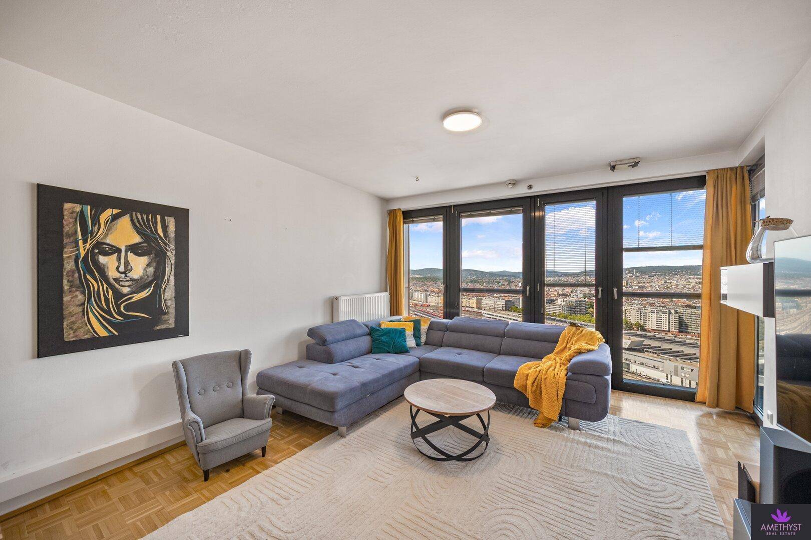 Gemütliches Wohnzimmer mit großem Ecksofa, Couchtisch und Panoramafenstern mit Stadtblick.