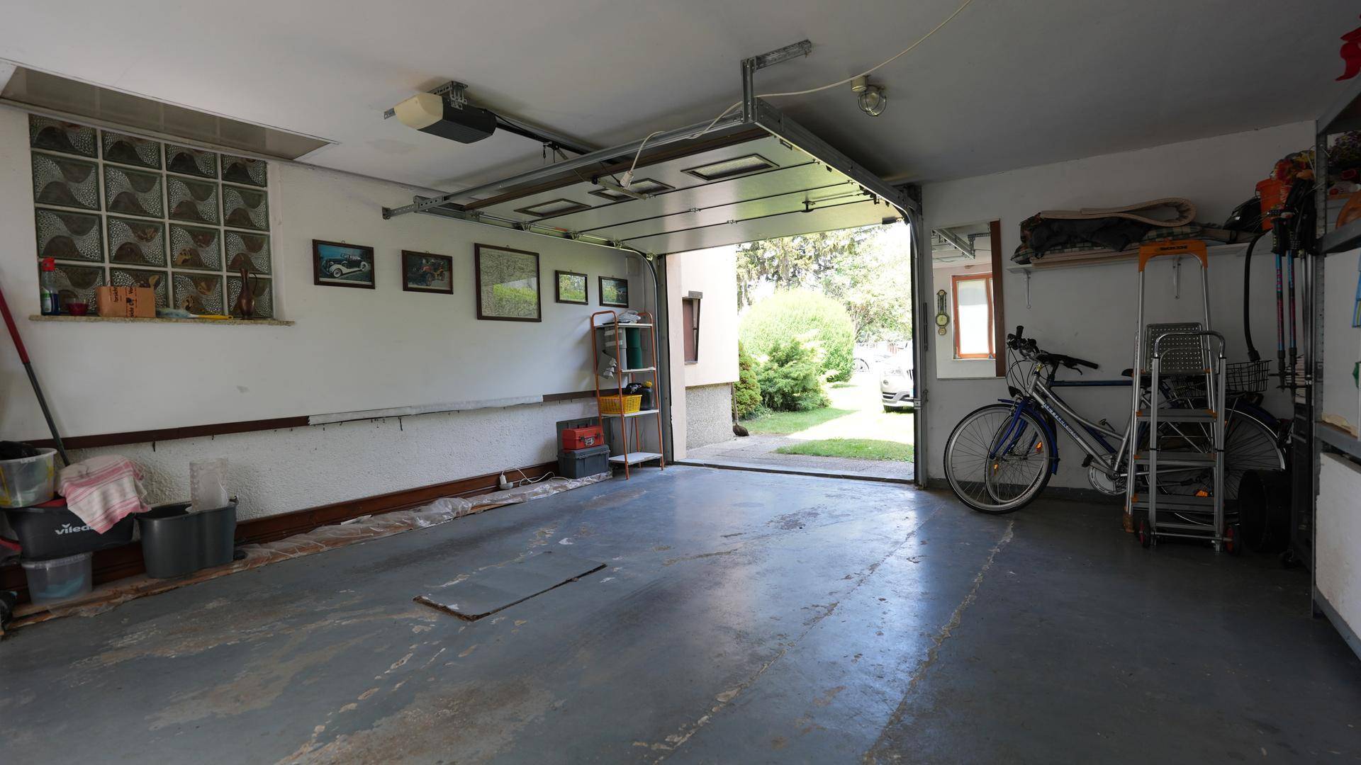 Helle Garage mit offenem Tor, Betonboden und ausreichend Platz für ein Fahrrad oder andere Gegenstände.