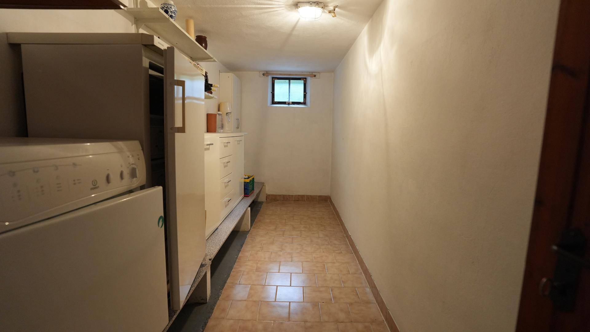 Praktischer Abstellraum mit Fliesenboden, kleinem Fenster und Haushaltsgeräten für den täglichen Gebrauch.