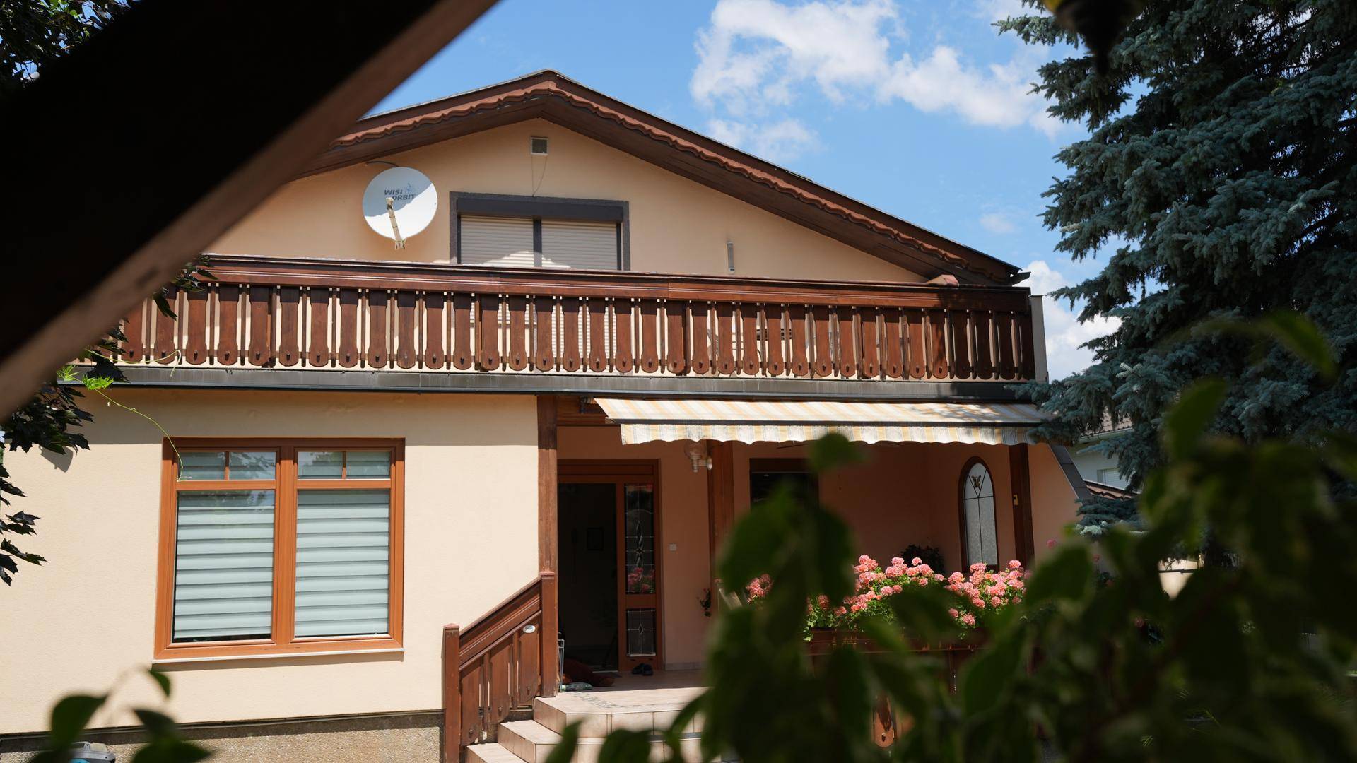 Traditionelle Hausfassade mit Holzbalkon, Markise und blühenden Blumenkästen.