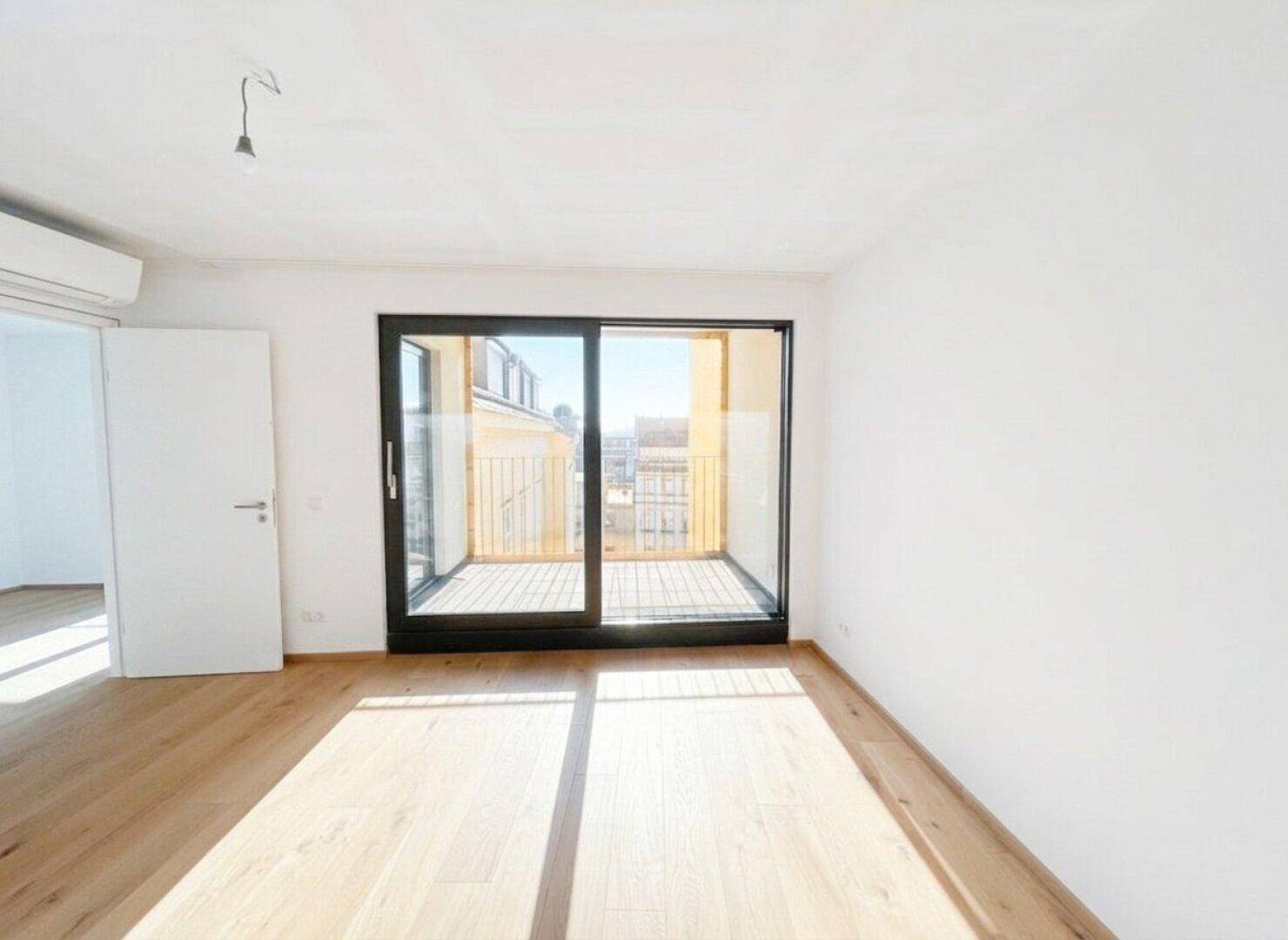 Helles Schlafzimmer mit Holzboden und direktem Zugang zu einem sonnigen Balkon.