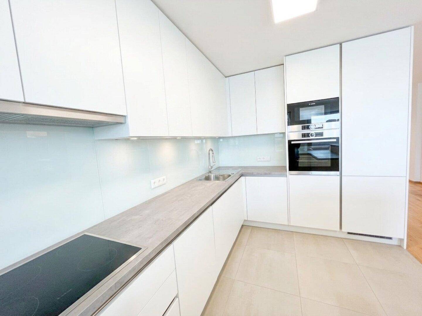 Hochwertige weiße Einbauküche mit Induktionskochfeld, Backofen und Mikrowelle.