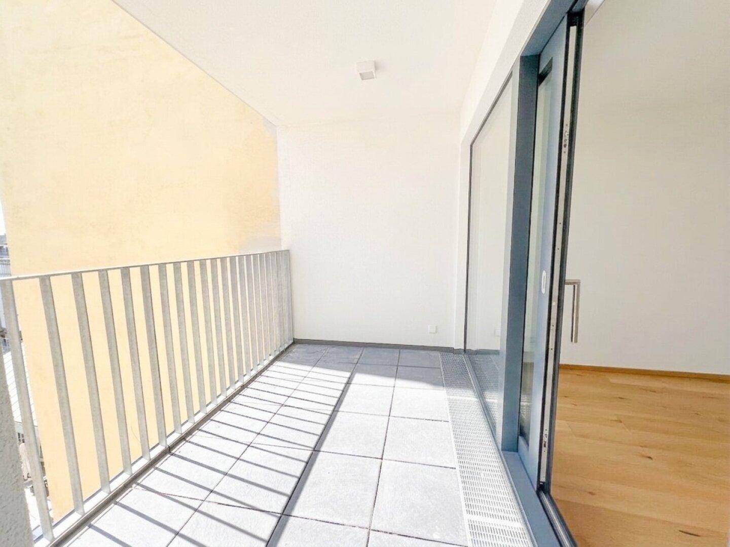 Heller Balkon mit Fliesenboden und Metallgeländer, bereit zur individuellen Gestaltung.