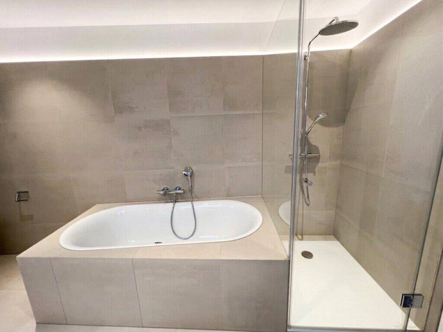 Elegantes Badezimmer mit eingebauter Badewanne und moderner Regendusche.