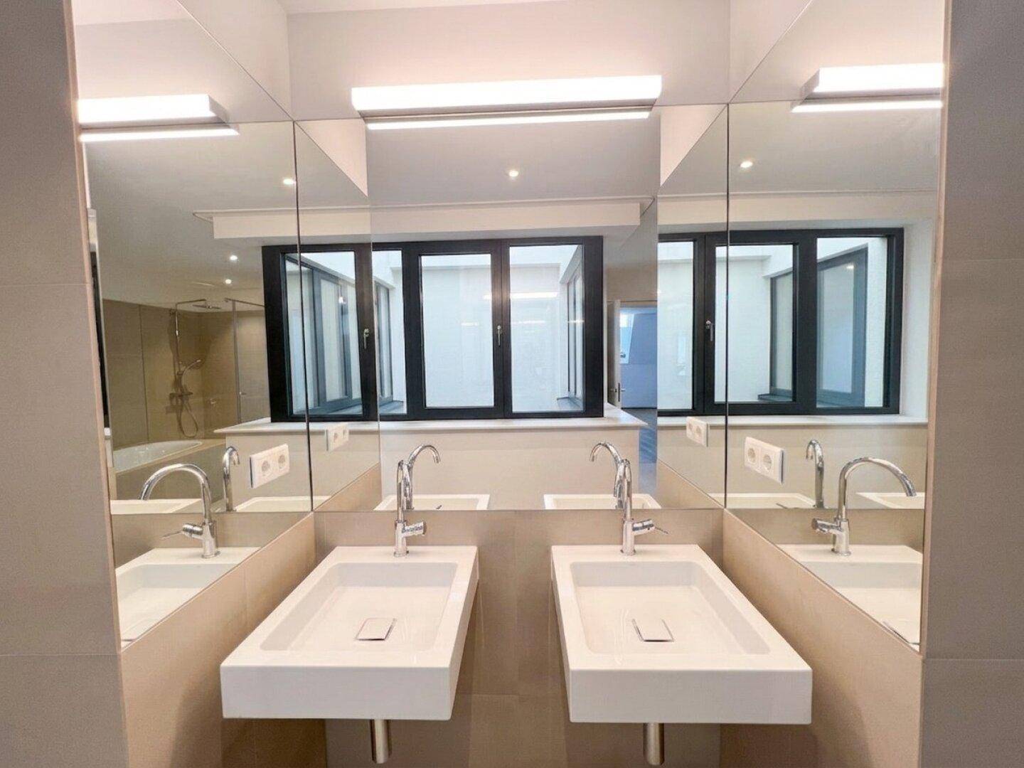 Doppelwaschbecken mit großem Spiegelschrank, der das helle Badezimmer reflektiert.