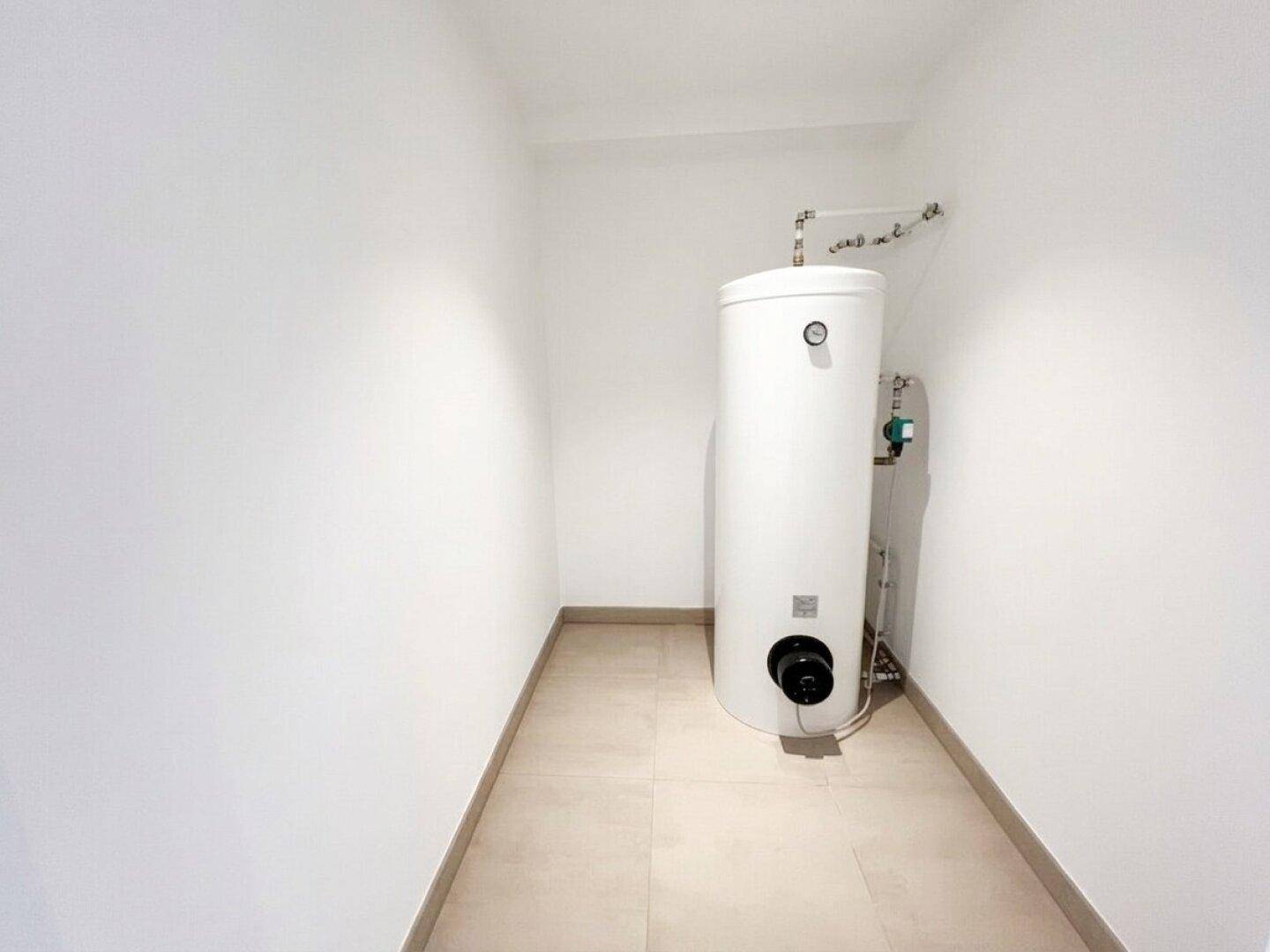 Kleiner Hauswirtschaftsraum mit Warmwasserspeicher und Fliesenboden.