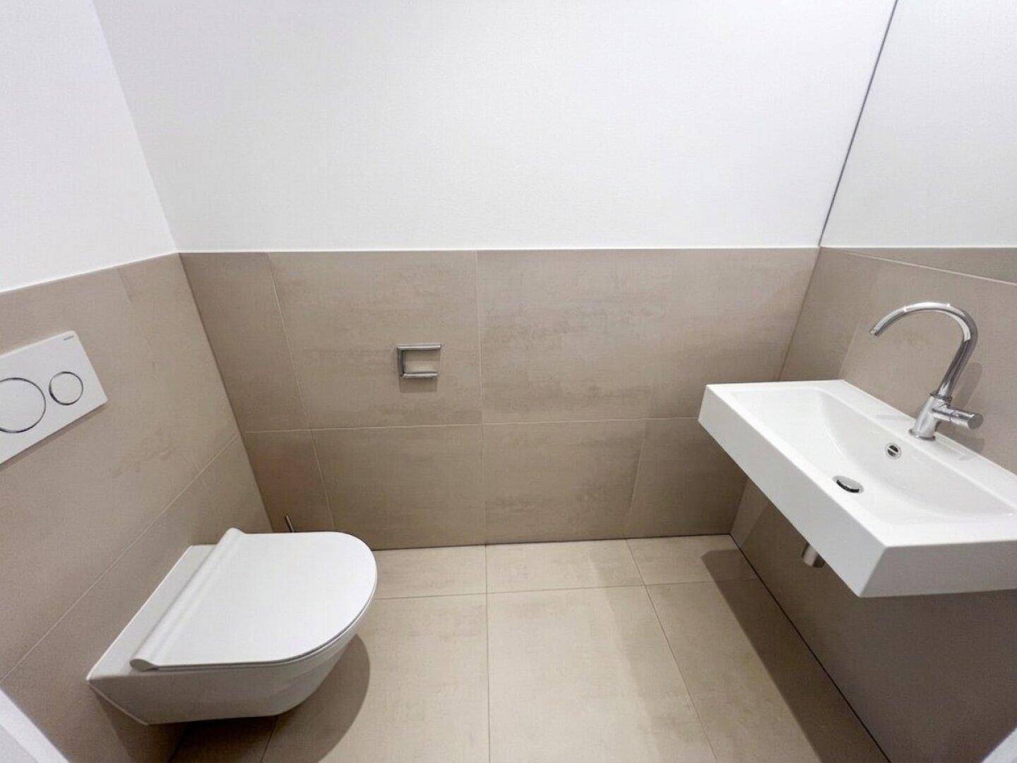 Modernes Gäste-WC mit wandhängender Toilette und kleinem Waschbecken.