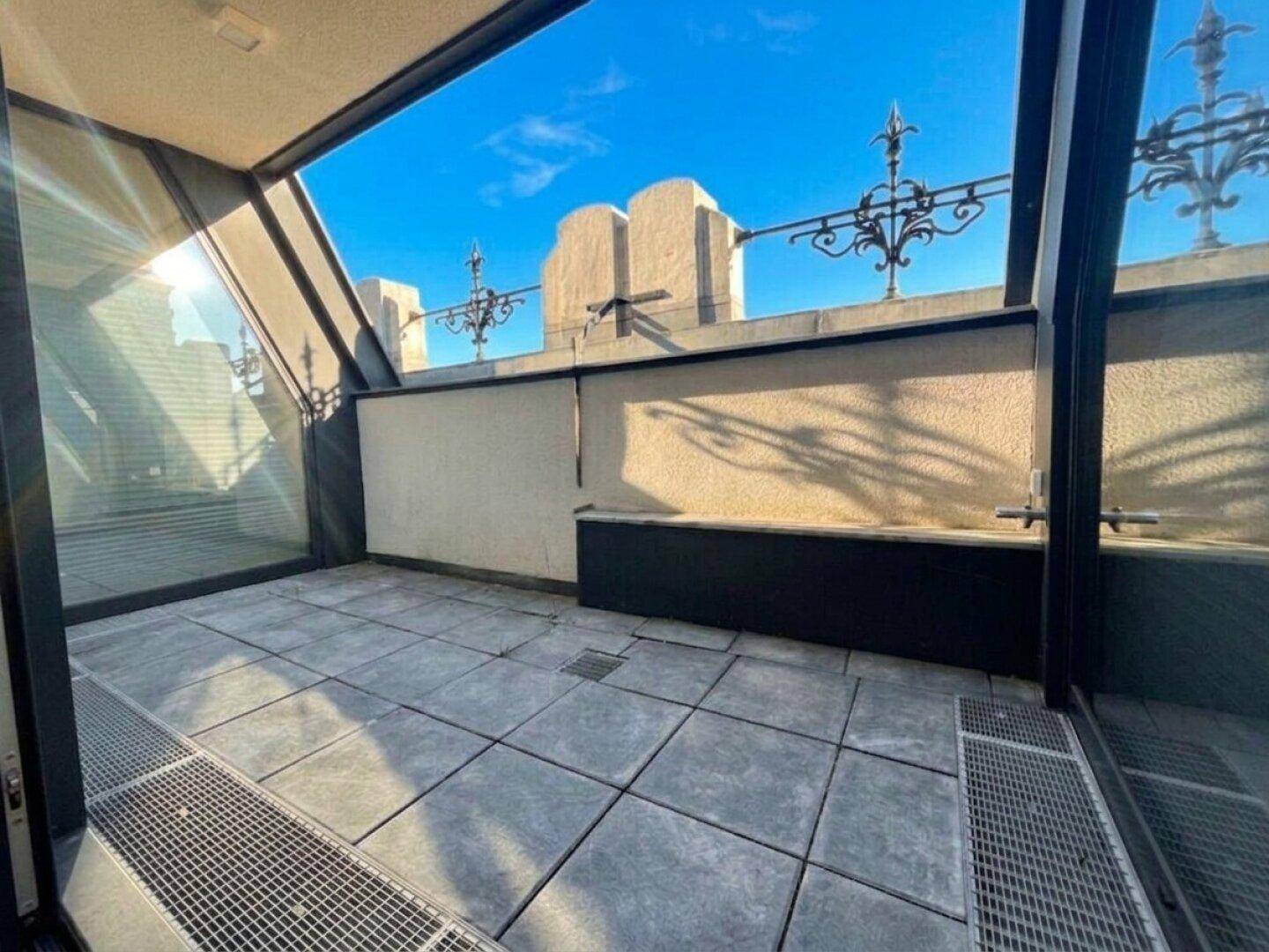 Sonnige Dachterrasse mit Fliesenboden und dekorativem Geländer, ideal zum Entspannen.