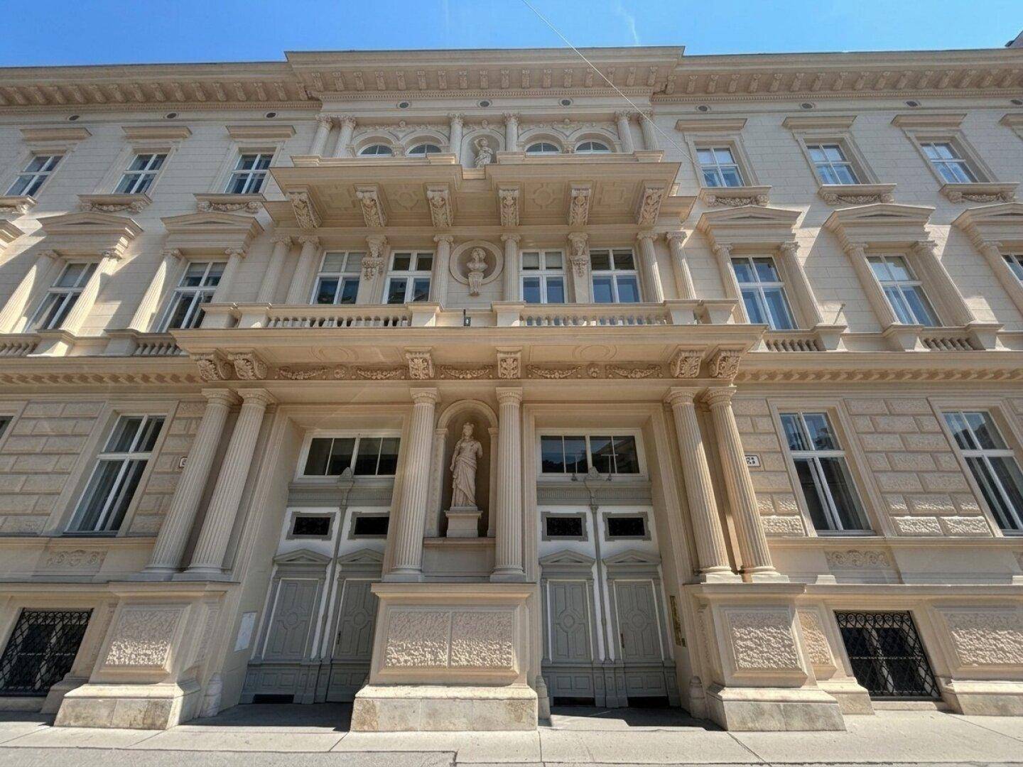 Prunkvolle historische Fassade eines Altbaus mit Säulen, Balkonen und aufwendigen Verzierungen.