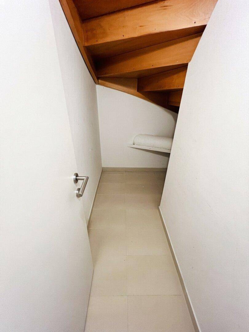 Praktischer Abstellraum unter der Treppe mit Fliesenboden und Stauraum.