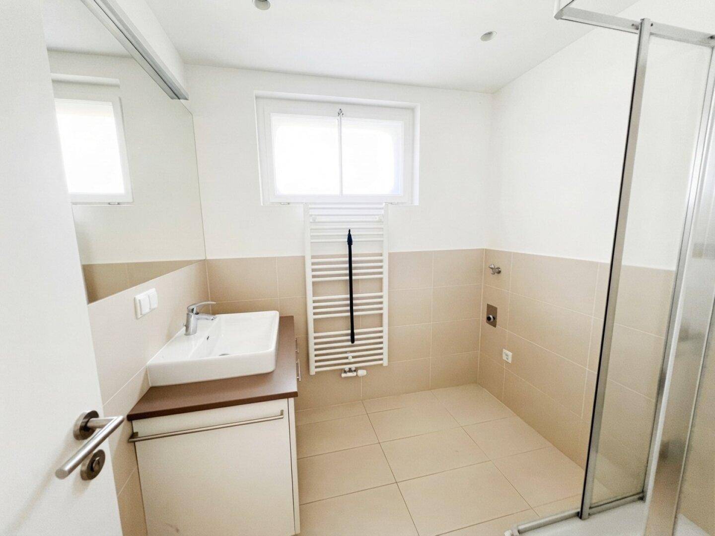 Modernes Badezimmer mit Dusche, Waschbecken und beheiztem Handtuchhalter.