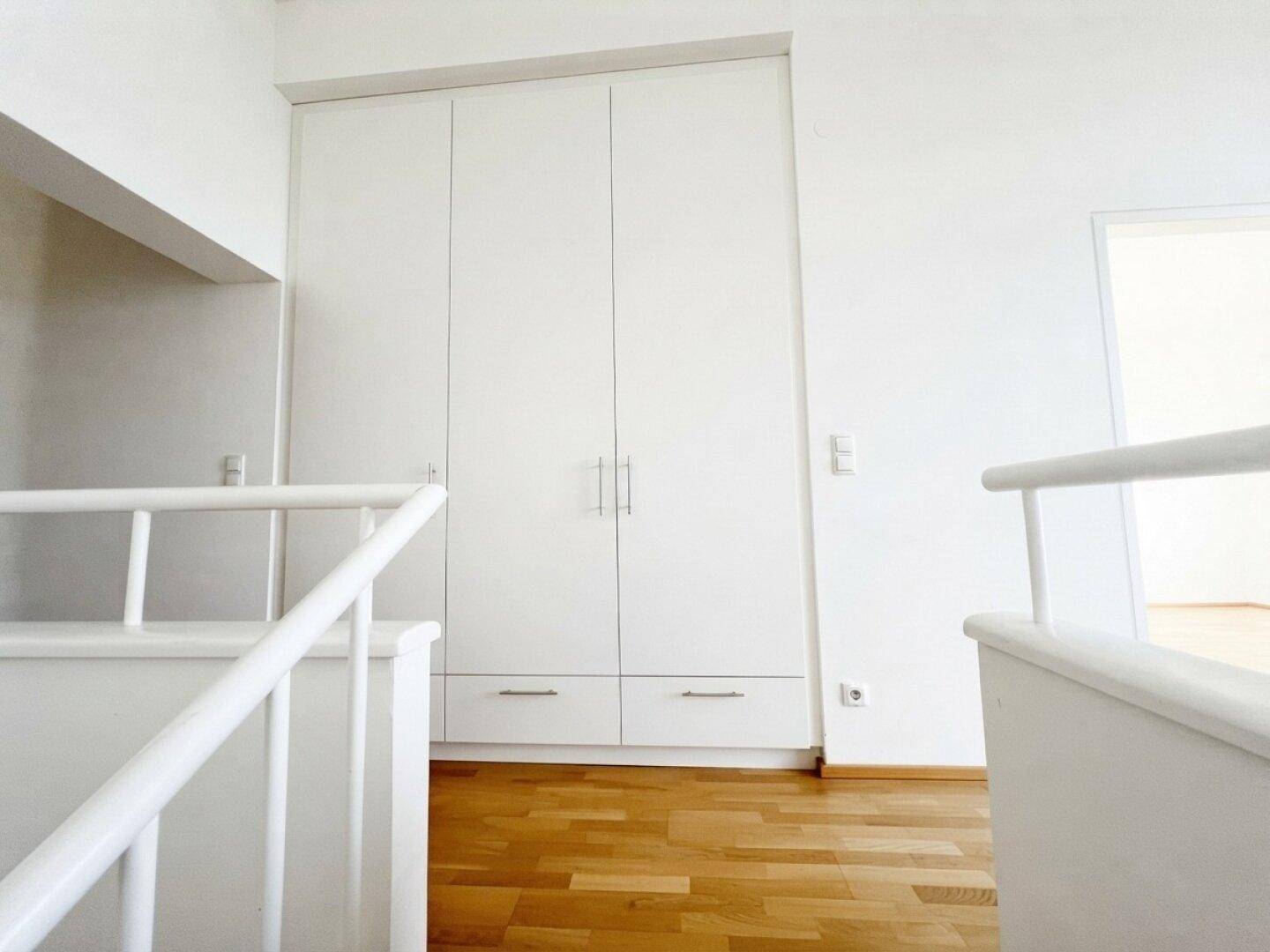 Obere Etage mit Einbauschrank, Parkettboden und Treppengeländer.