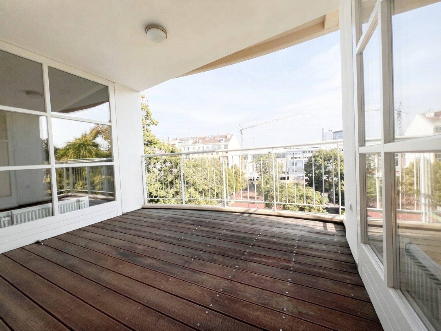 Geräumiger Balkon mit Holzboden und weitem Blick über die Stadt.