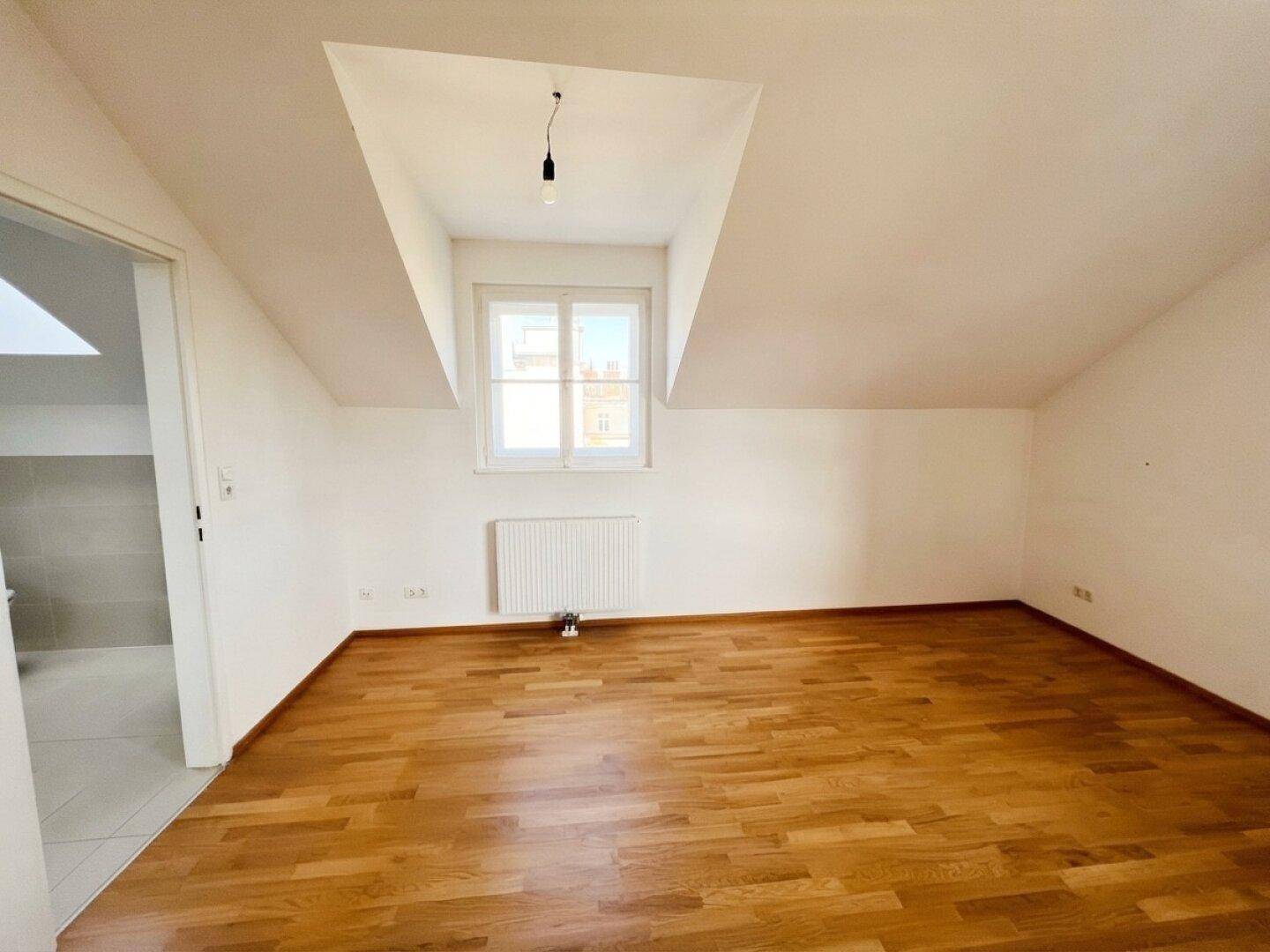 Helles Schlafzimmer im Dachgeschoss mit Parkettboden und Dachschräge.