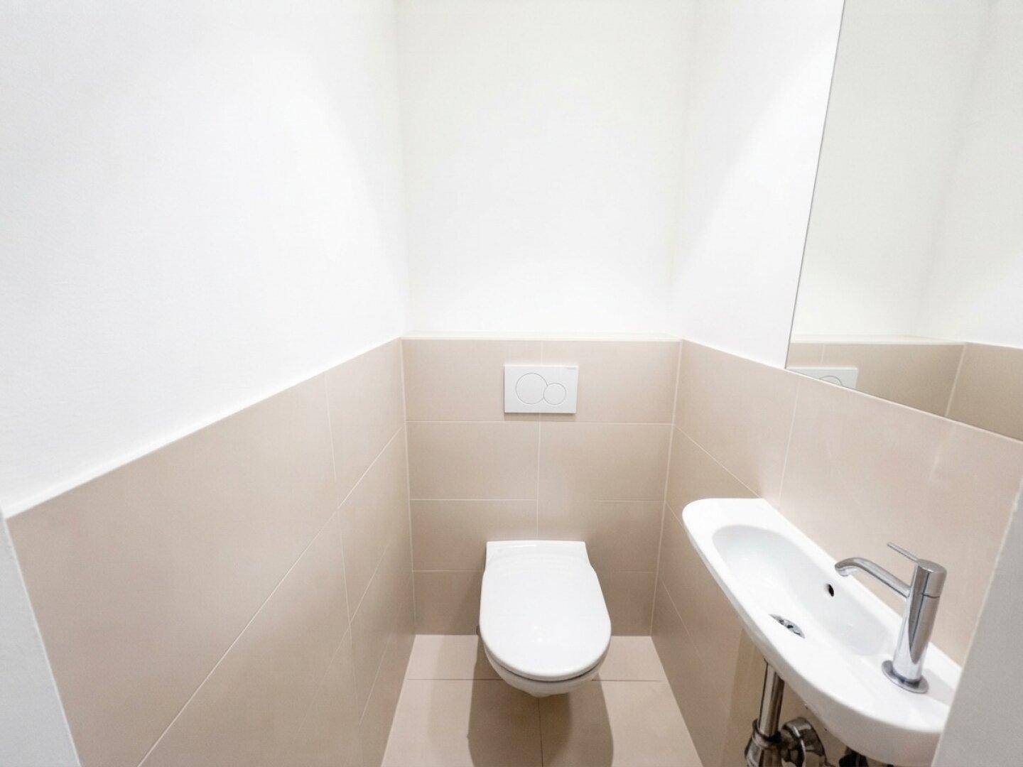 Modernes Gäste-WC mit wandhängendem WC und kleinem Waschbecken.