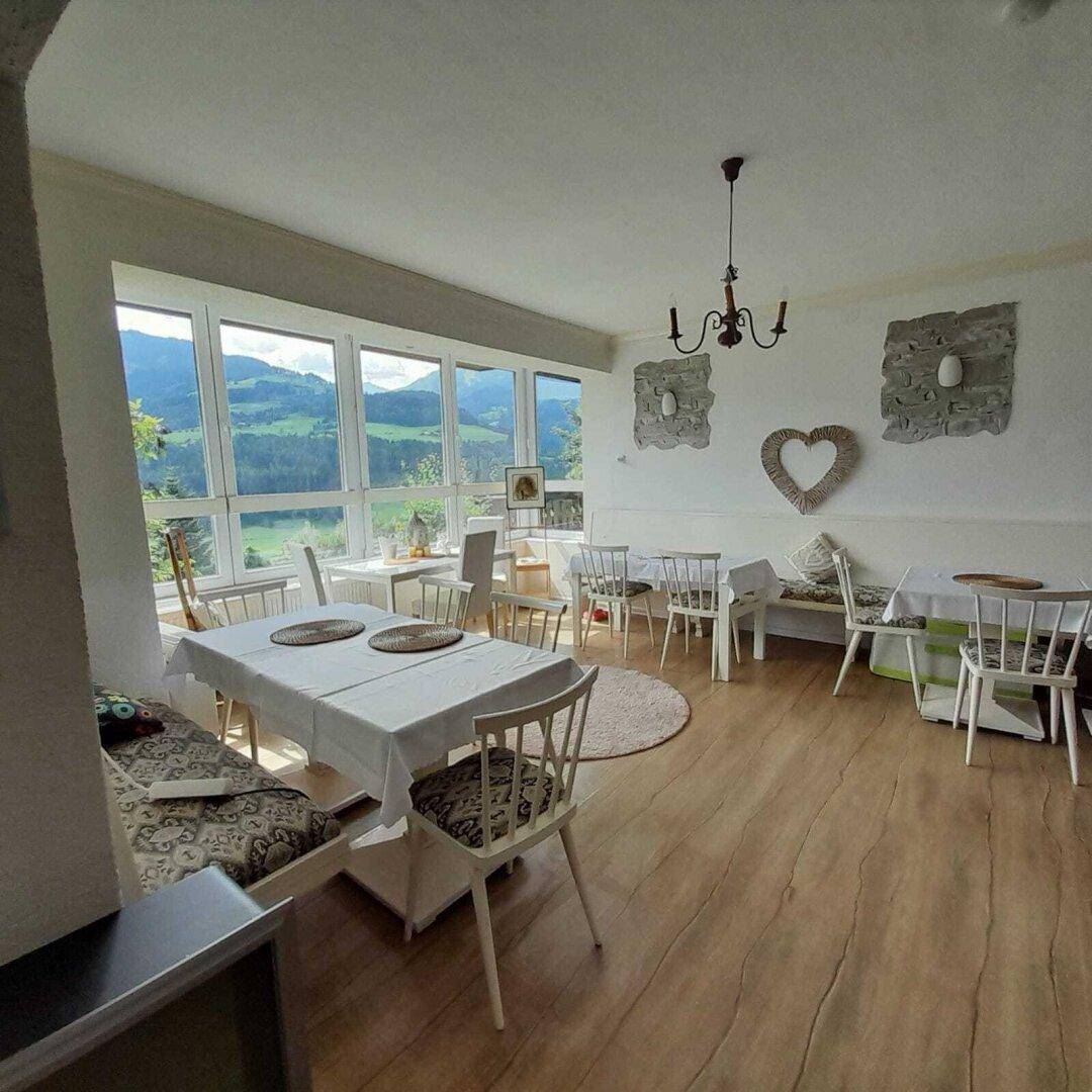 Heller Essbereich mit großen Fenstern, die einen Panoramablick auf die grüne Berglandschaft bieten.