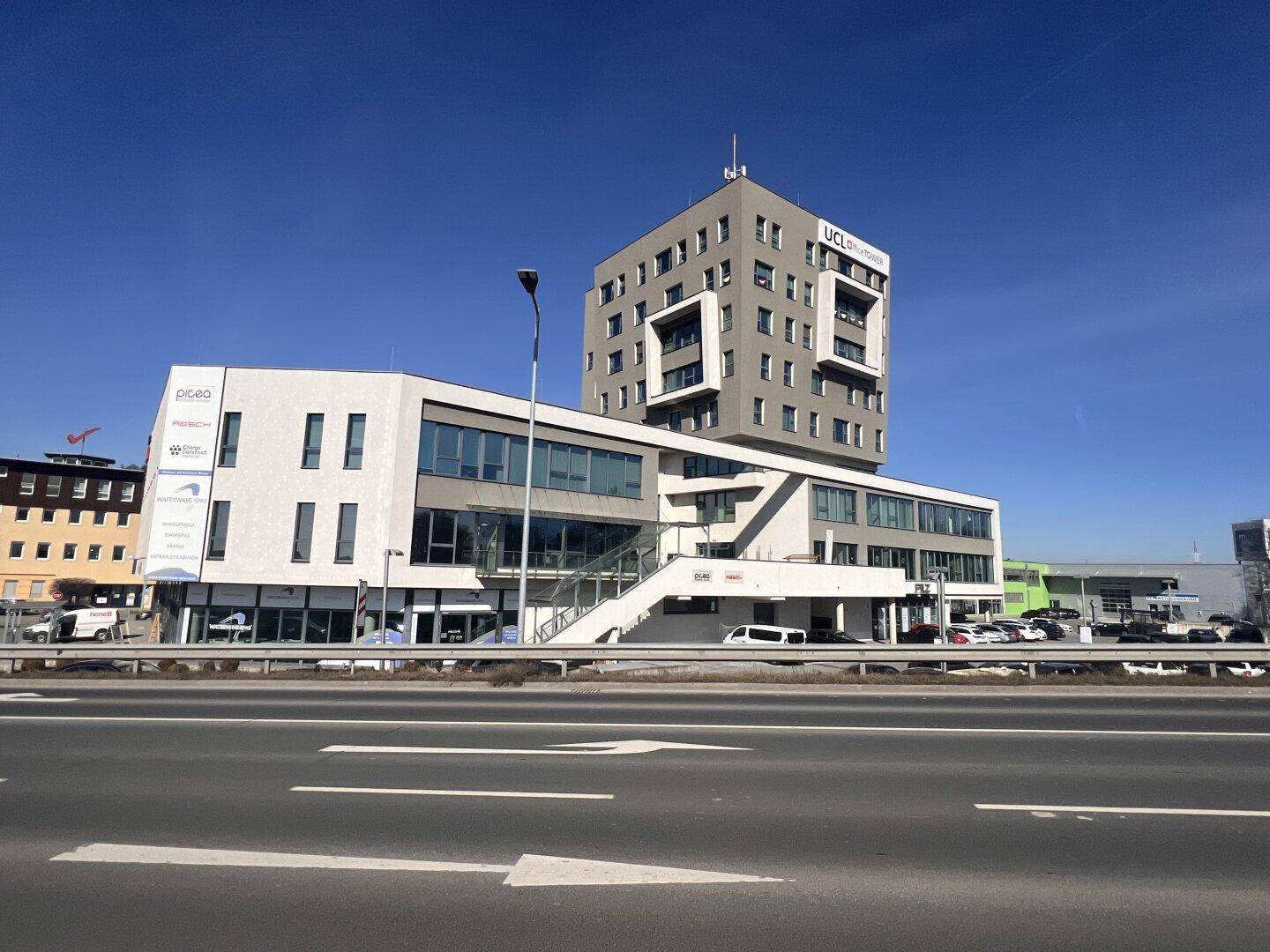 Modernes Geschäftsgebäude mit markanter Architektur und mehreren Etagen, sichtbar von der Straße aus.
