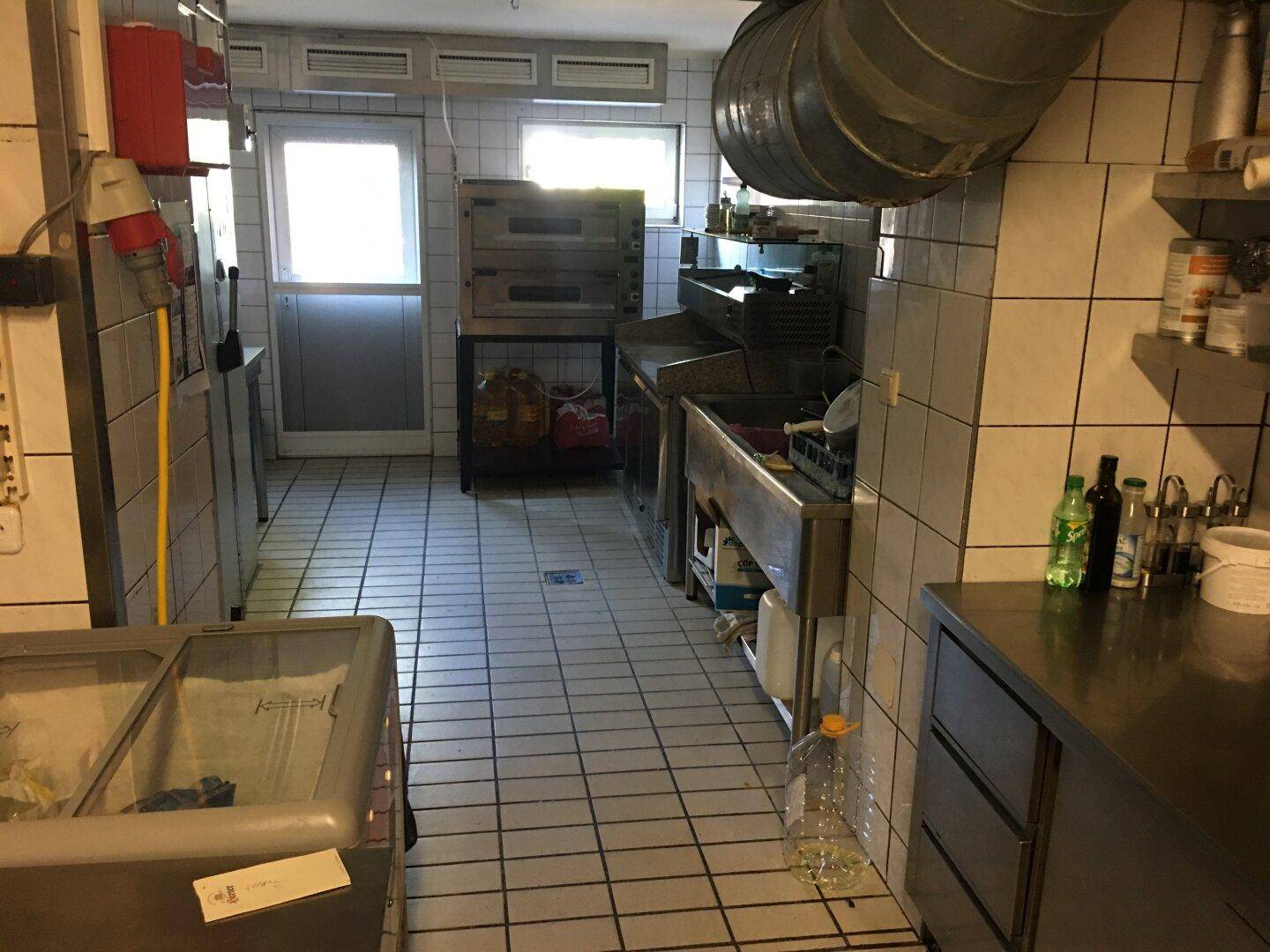 Geräumige Gewerbeküche mit Fliesenboden, großen Fenstern und professionellen Geräten.
