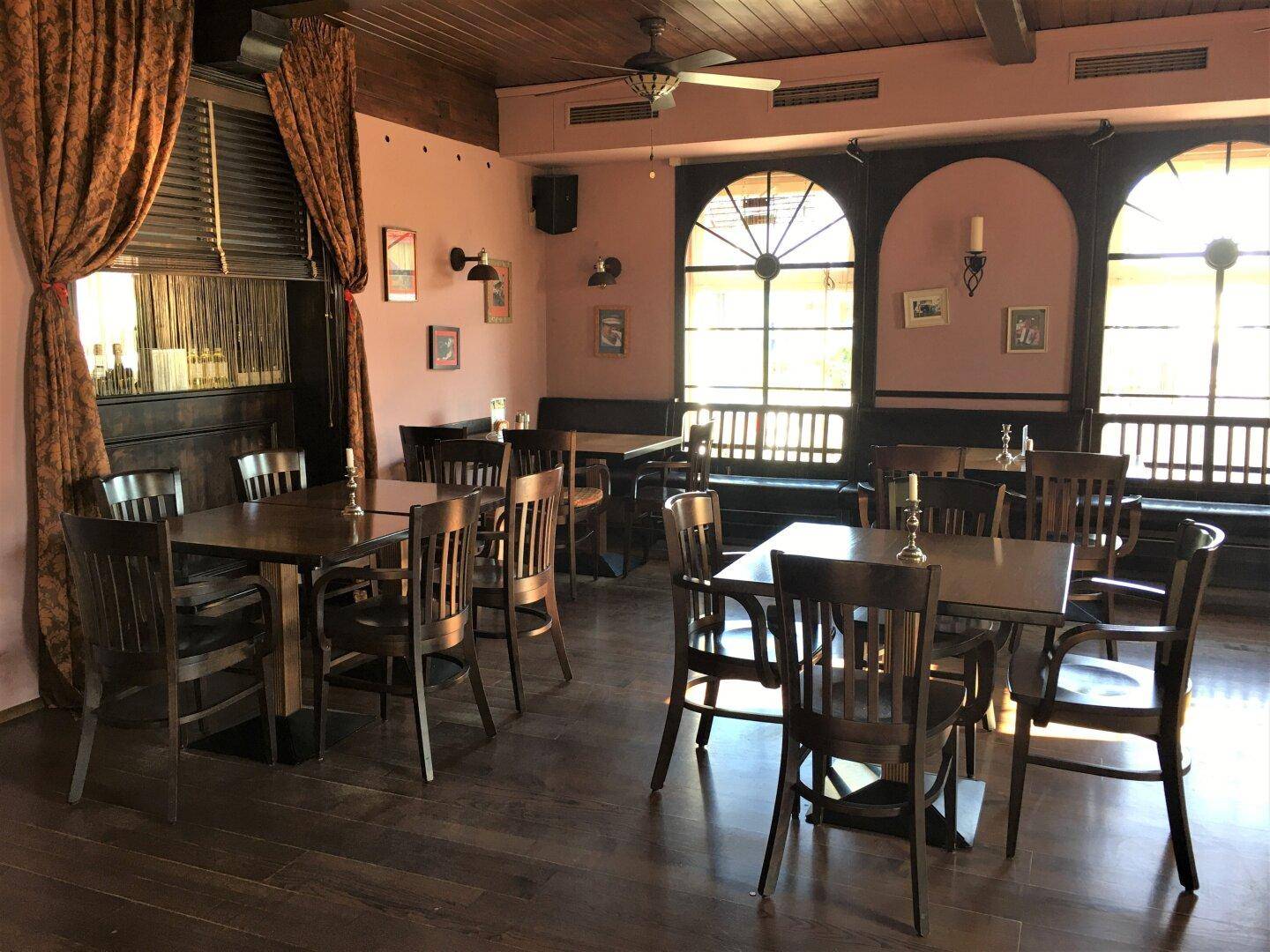 Traditioneller Essbereich mit Holztischen und Stühlen, großen Bogenfenstern und dunklem Holzboden.