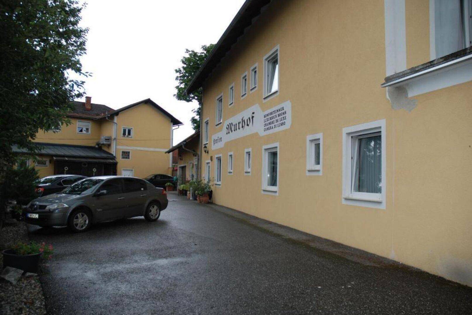 Lange Seitenansicht eines gelben Gebäudes mit vielen Fenstern und einem Parkplatzbereich.