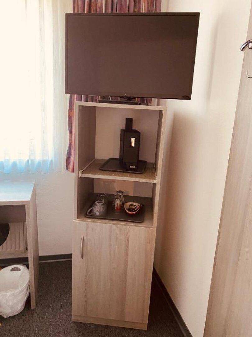 Detailansicht eines Schranks mit Fernseher, Kaffeemaschine und Ablageflächen im Schlafzimmer.