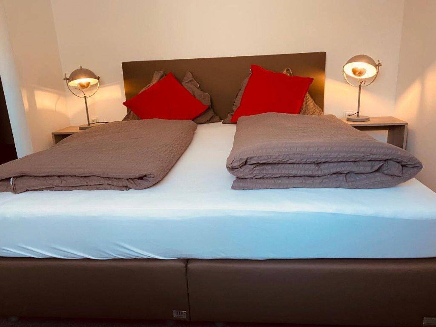 Komfortables Doppelbett mit Nachttischen und modernen Lampen, bereit für Gäste.