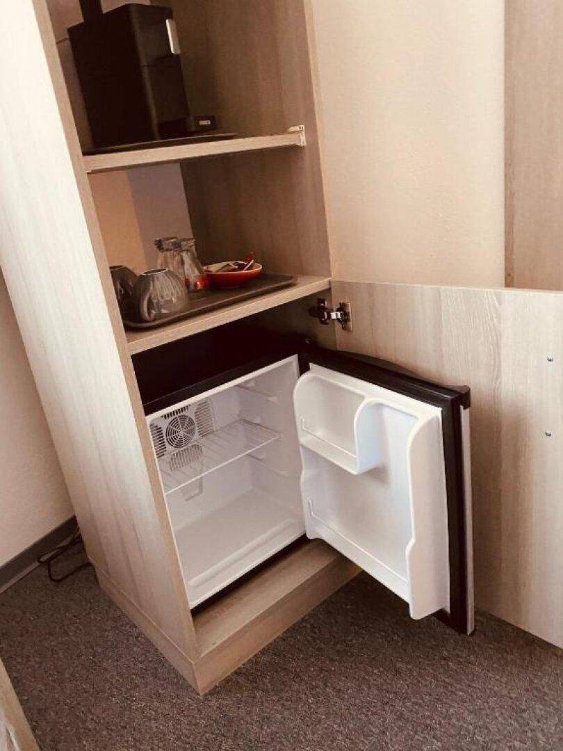 Offener Minikühlschrank in einem Schrank im Schlafzimmer, praktisch für Getränke.