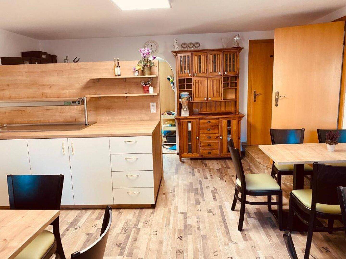 Gemütlicher Frühstücksraum mit Buffet, Holztischen und einem traditionellen Holzschrank.