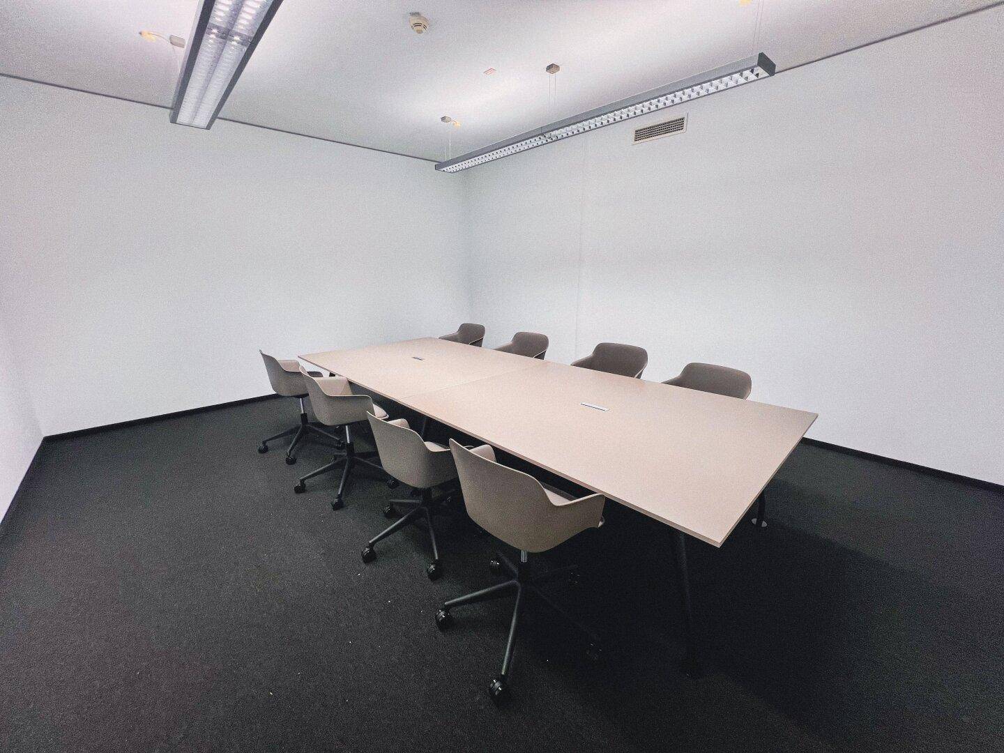 Geräumiger Konferenzraum mit einem langen Tisch und mehreren Bürostühlen, ideal für Besprechungen.
