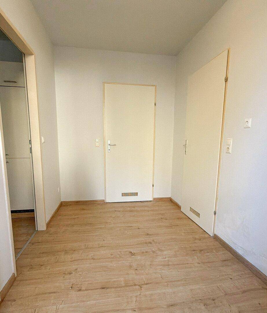 Heller Flur mit Laminatboden und mehreren Türen, der zu anderen Räumen führt.