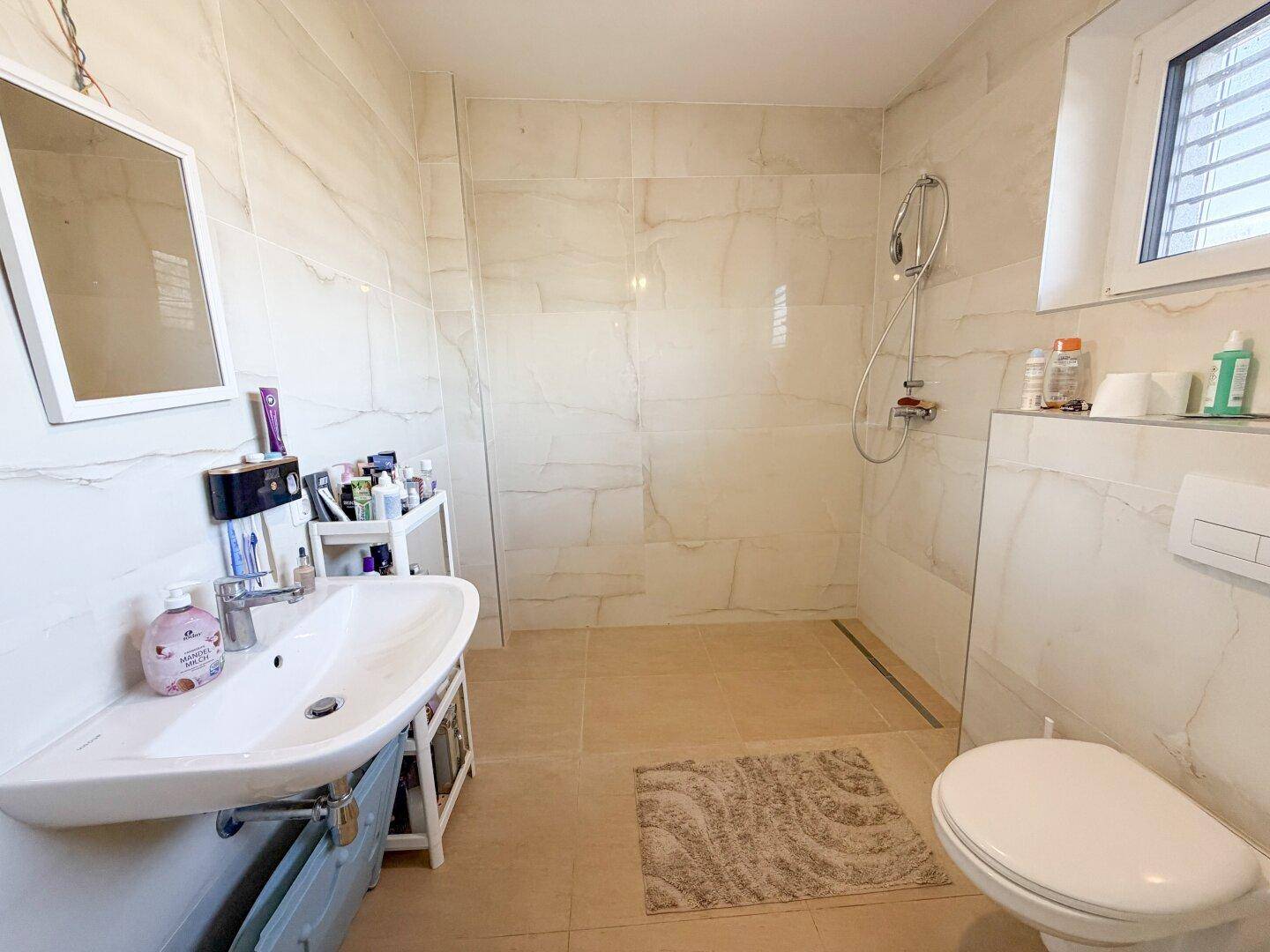 Modernes Badezimmer mit begehbarer Dusche, Wand-WC und eleganten Fliesen, hell und pflegeleicht.
