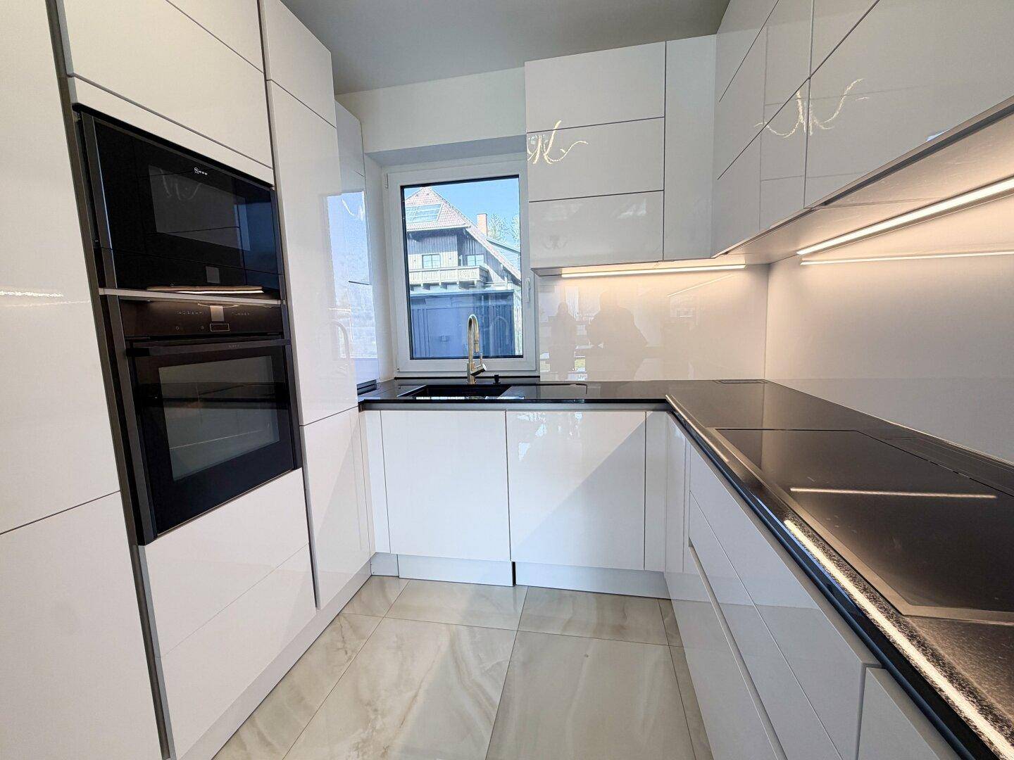 Elegante weiße Küche mit integriertem Backofen und Kochfeld, bietet viel Arbeitsfläche und Stauraum.