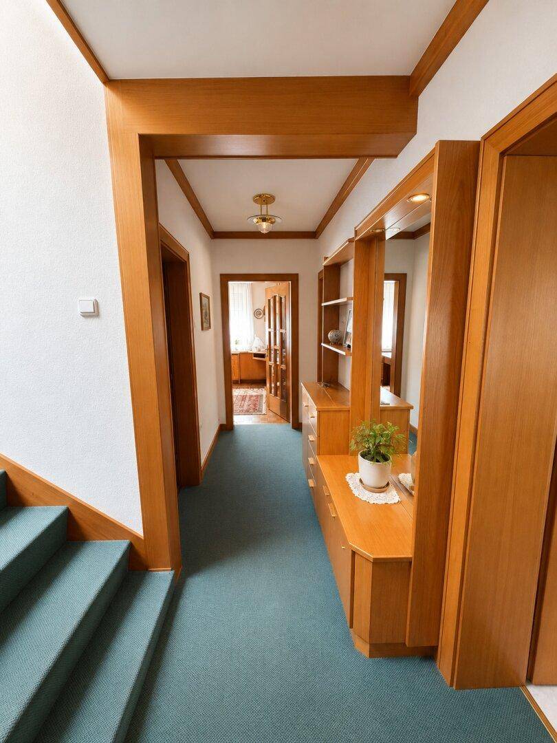 Heller Flur mit Holzvertäfelung, Teppichboden und Blick auf die Treppe, sauber und ordentlich.
