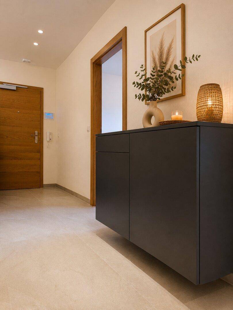 Heller Eingangsbereich mit modernem Sideboard, Holztür und Fliesenboden.