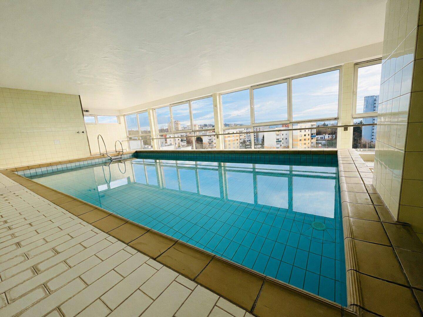Innenpool mit großen Fenstern und Panoramablick über die Stadt.
