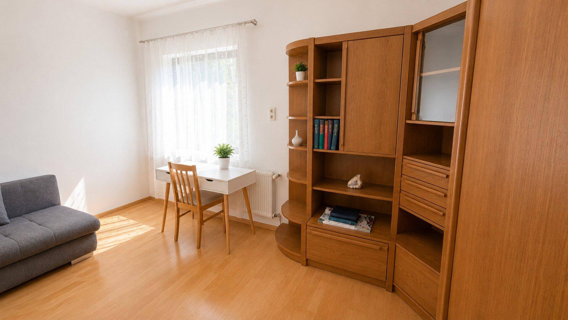 Helles Arbeitszimmer mit Schreibtisch, Sofa und Holzregal, ideal für Home-Office.