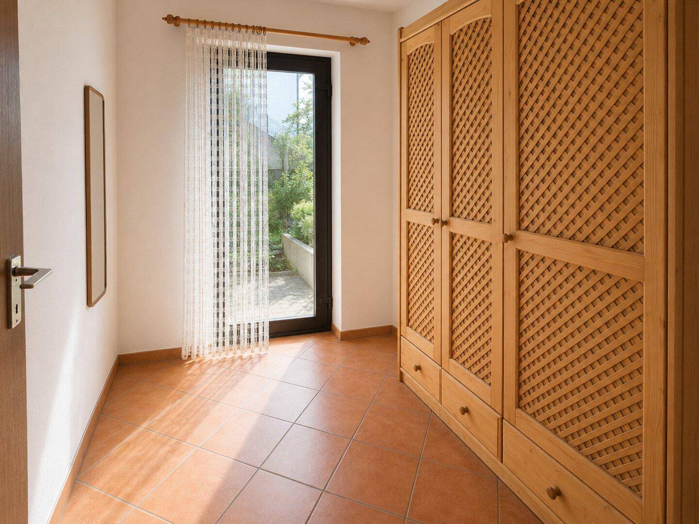 Flur mit Terrakotta-Fliesen, großem Holzschrank und Zugang zum Außenbereich.