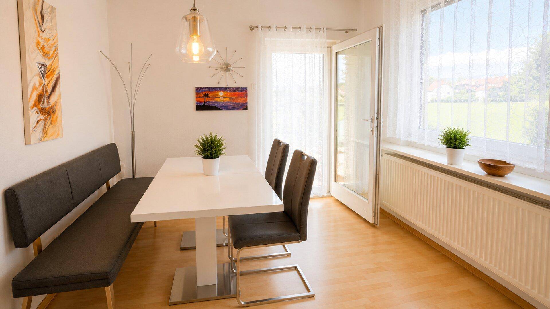 Heller Essbereich mit modernem Tisch, Sitzbank und Zugang zum Außenbereich.