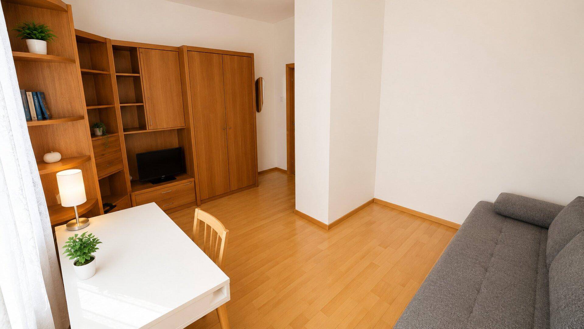 Funktionales Arbeitszimmer mit Holzregal, Schreibtisch und Sofa in heller Atmosphäre.